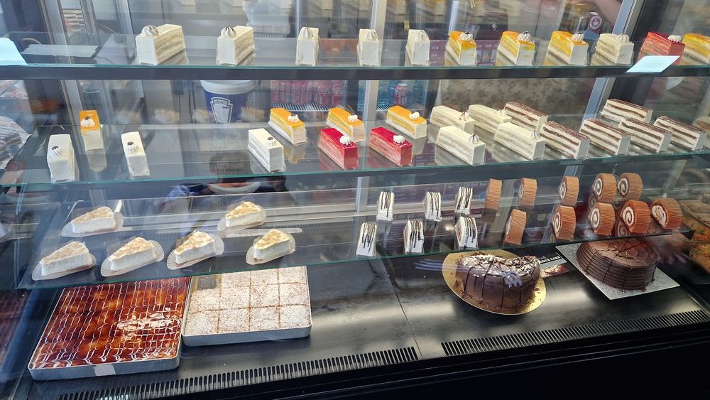 The full length of the cake counter at Cafe Royal, packed with slices and tarts behind glass.